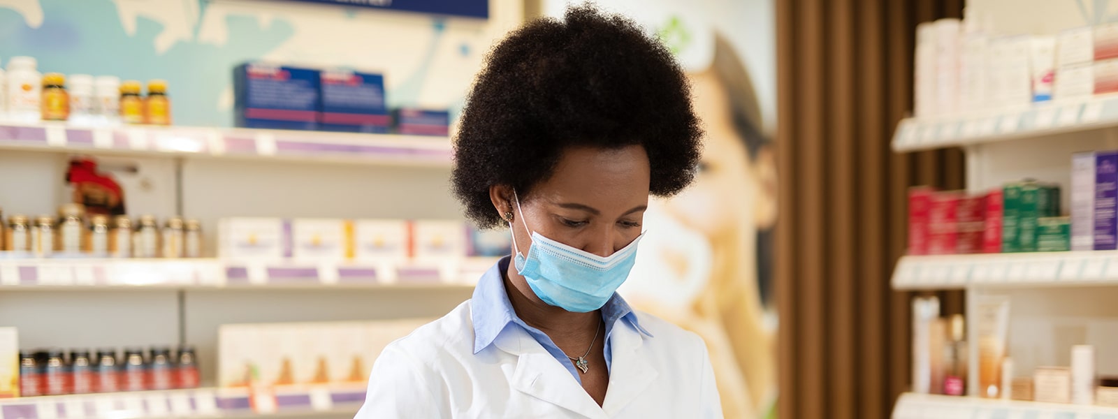 A pharmacist wearing a mask is busy at work.
